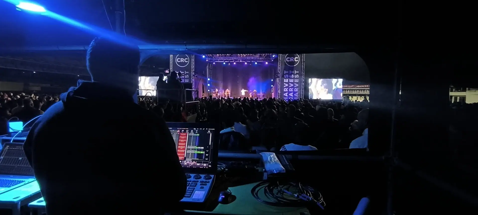 Lighting console at front of house with the CRC Harvest stage and a full stadium beyond